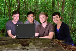 Four students around a laptop in a park